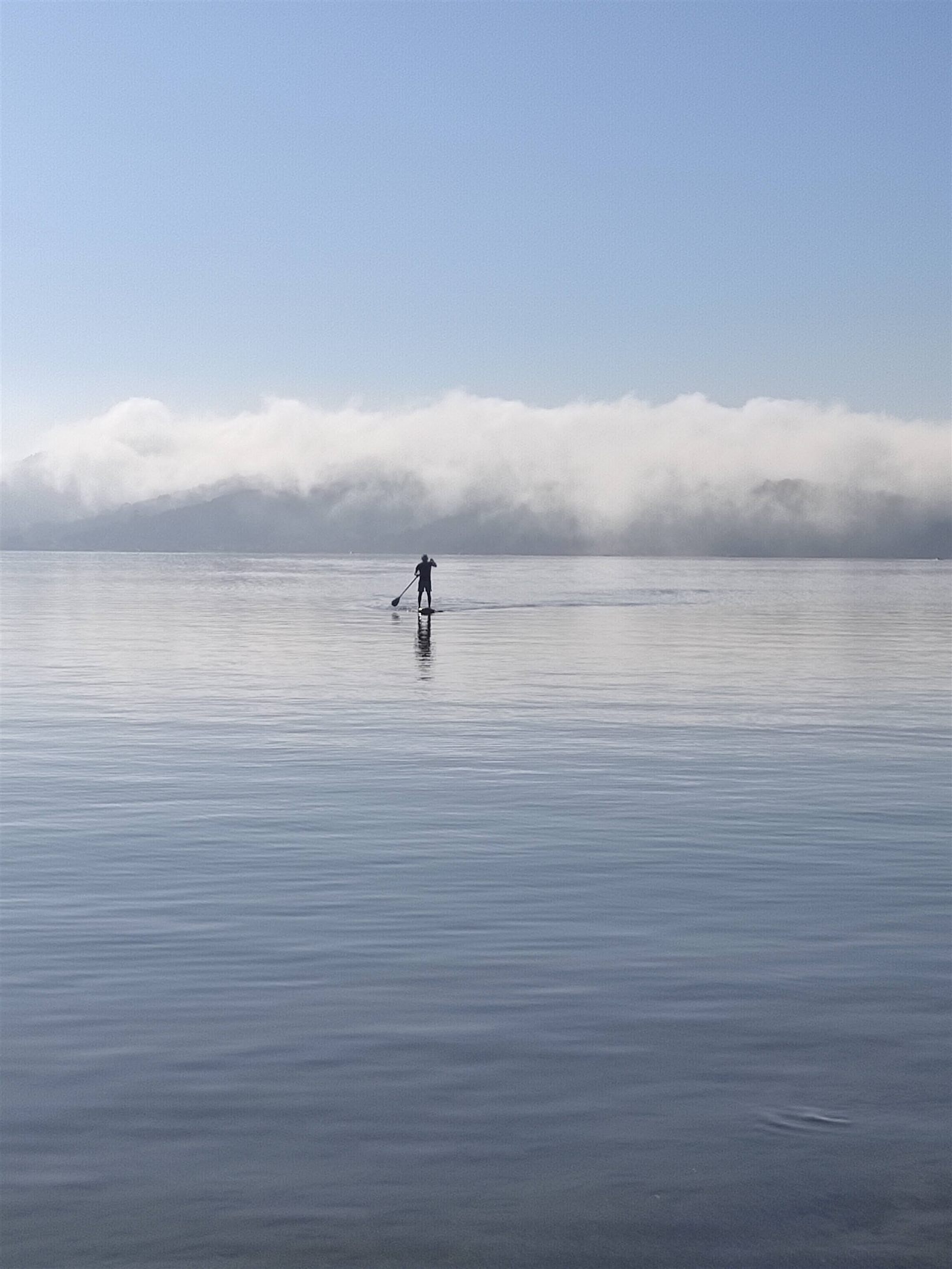 Stand up paddle na lagoa calma ao amanhecer, com névoa sobre os morros